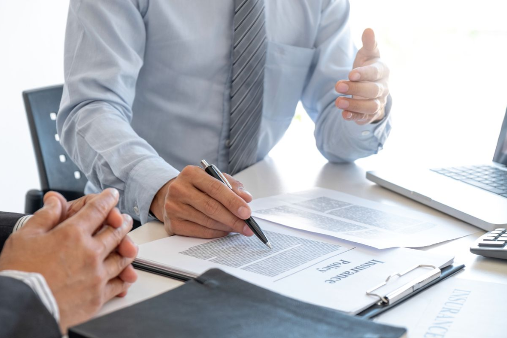 a man in a tie working on paperwork with another man.